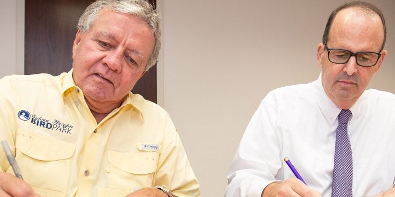 Sylvan Heights Bird Park board of directors chairman Don Butler (from left) and East Carolina University vice chancellor for research, economic development and engagement Jay Golden ink a collaboration agreement between Sylvan Heights and ECU. (ECU News Services)